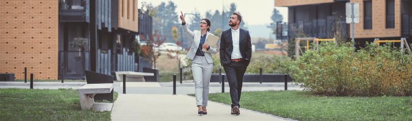 Two colleagues walking through a college campus looking at the buildings